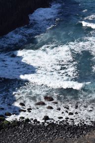 White waves against a dark rocky lava beach